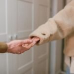 Close-up of two people holding hands indoors, indicating connection and support.