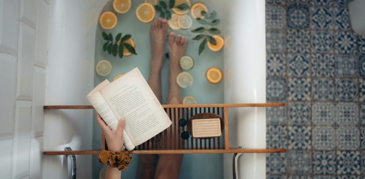 A tranquil bathtub with citrus fruits, book, and self-care essentials for relaxation.