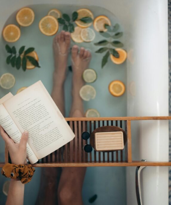 A tranquil bathtub with citrus fruits, book, and self-care essentials for relaxation.