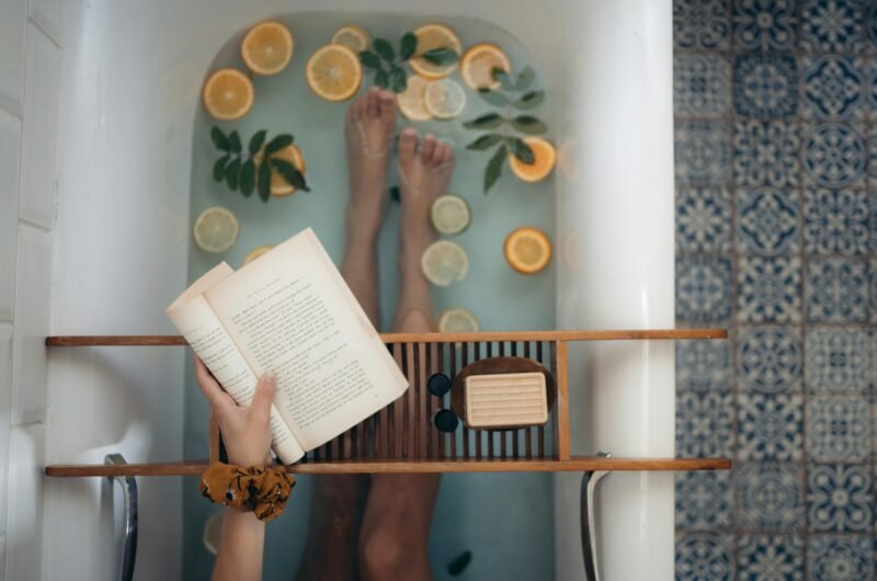 A tranquil bathtub with citrus fruits, book, and self-care essentials for relaxation.