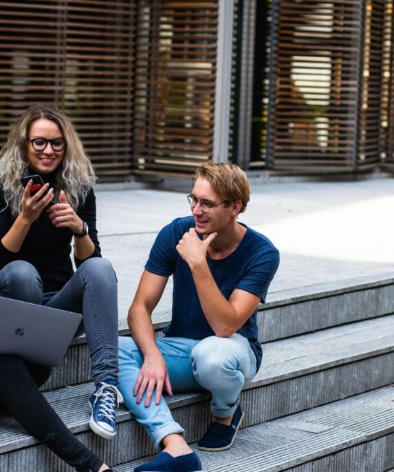 Three young professionals having a friendly chat while sitting on outdoor steps.