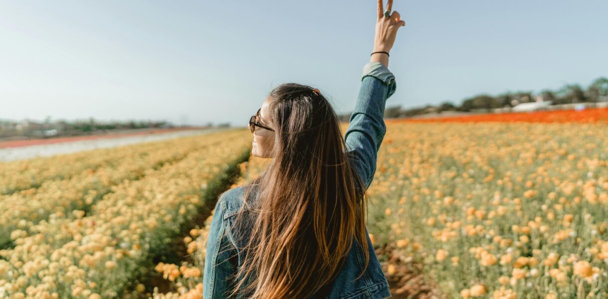 A woman enjoying a sunny day in a vivid yellow flower field in Carlsbad, CA.