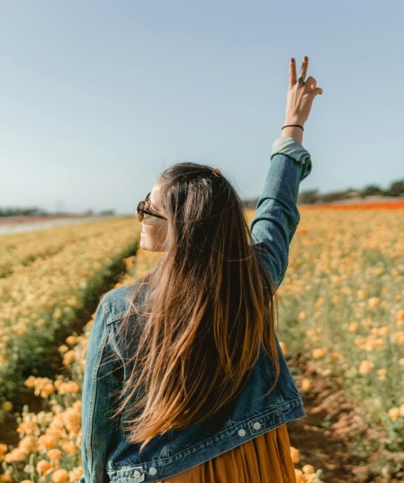 A woman enjoying a sunny day in a vivid yellow flower field in Carlsbad, CA.